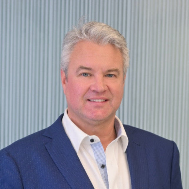 Peter Dingle wearing a blue suit and white shirt against a gray background